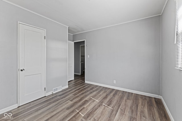 unfurnished bedroom with crown molding, wood finished floors, and baseboards