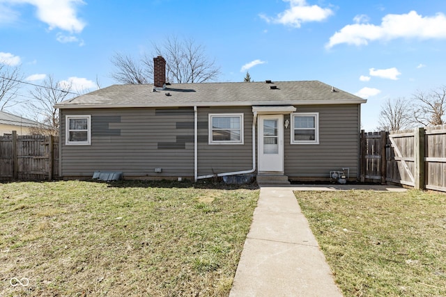 rear view of property featuring a gate, entry steps, fence, a yard, and a chimney