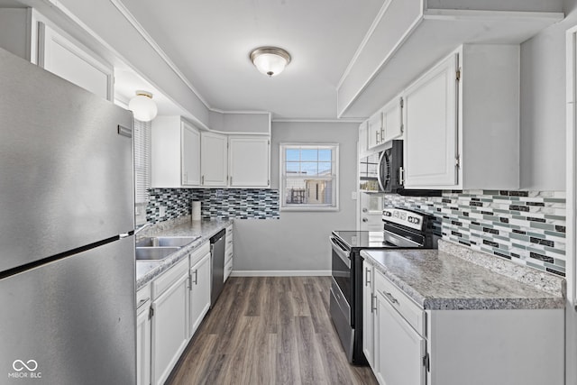 kitchen with a sink, dark wood-style floors, stainless steel appliances, white cabinets, and light countertops