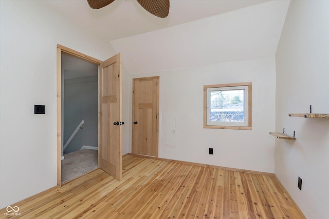 unfurnished bedroom featuring a closet, lofted ceiling, light wood-style floors, and ceiling fan