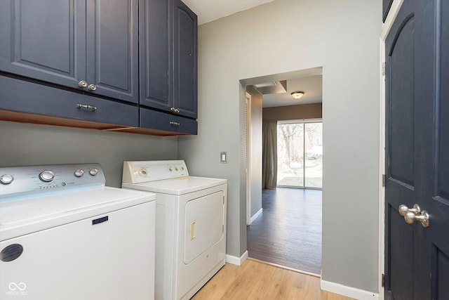 washroom featuring baseboards, cabinet space, light wood-type flooring, and washing machine and clothes dryer