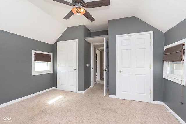 unfurnished bedroom featuring baseboards, lofted ceiling, and light colored carpet