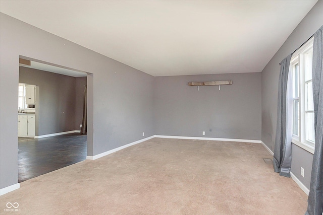 carpeted empty room featuring baseboards