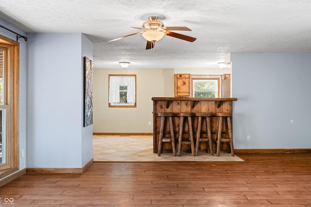 unfurnished dining area with plenty of natural light, a textured ceiling, and wood-type flooring