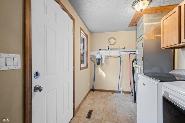 washroom with baseboards, washer and clothes dryer, light tile patterned flooring, cabinet space, and a textured ceiling