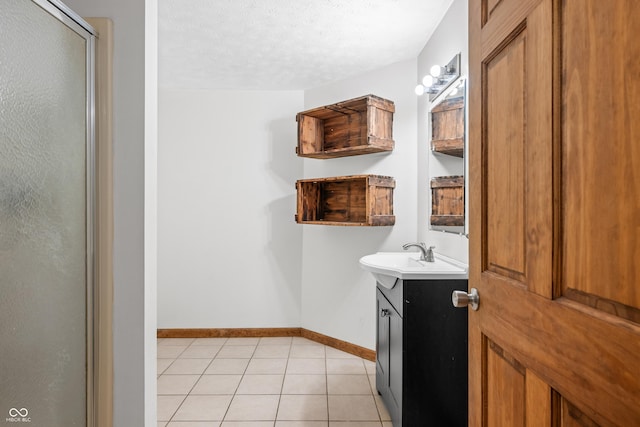 full bathroom with tile patterned floors, an enclosed shower, a textured ceiling, baseboards, and vanity