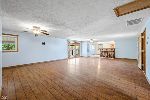 unfurnished living room featuring baseboards, visible vents, wood-type flooring, and ceiling fan