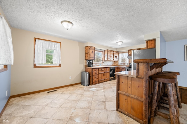 kitchen with a sink, stainless steel appliances, a wealth of natural light, and brown cabinetry