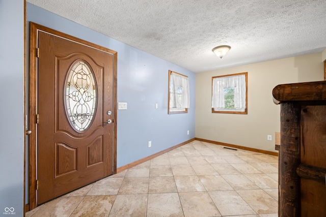 foyer with light tile patterned flooring, visible vents, baseboards, and a textured ceiling