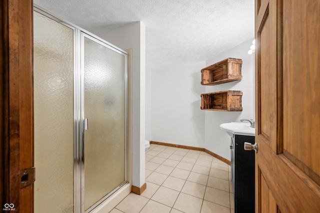 full bath with tile patterned floors, a shower stall, and a textured ceiling