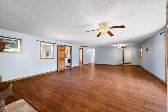 unfurnished living room with ceiling fan, a textured ceiling, baseboards, and hardwood / wood-style flooring