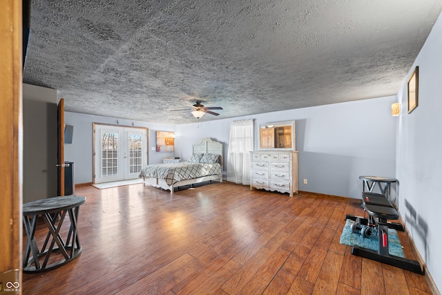 bedroom featuring ceiling fan, baseboards, hardwood / wood-style floors, french doors, and a textured ceiling