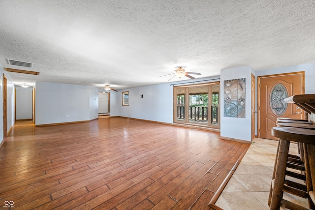 unfurnished living room with visible vents, baseboards, light wood-style floors, and a ceiling fan