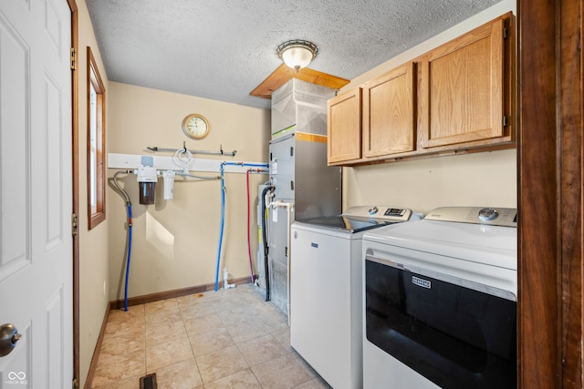 clothes washing area with baseboards, visible vents, cabinet space, a textured ceiling, and washer and dryer