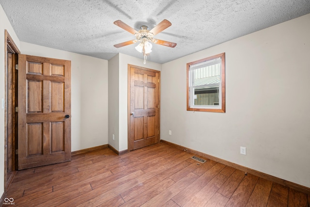 unfurnished bedroom with light wood-type flooring, baseboards, a textured ceiling, and visible vents