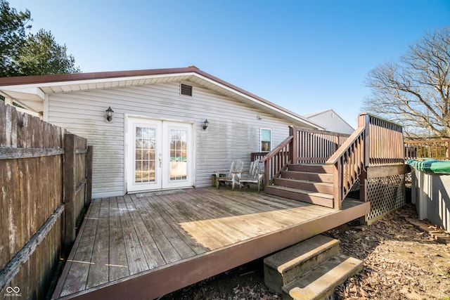 rear view of property featuring french doors, fence, and a wooden deck