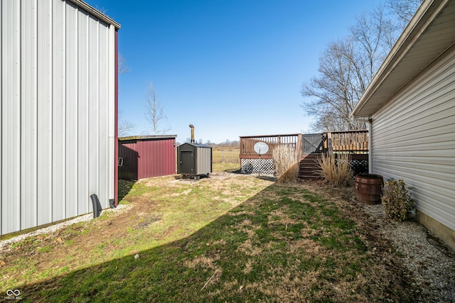 view of yard with a deck, an outbuilding, and a shed