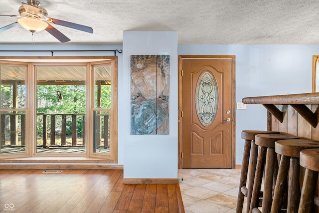 entrance foyer featuring a ceiling fan, light wood-style floors, visible vents, and a textured ceiling