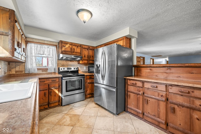 kitchen with brown cabinetry, a sink, stainless steel appliances, under cabinet range hood, and tasteful backsplash