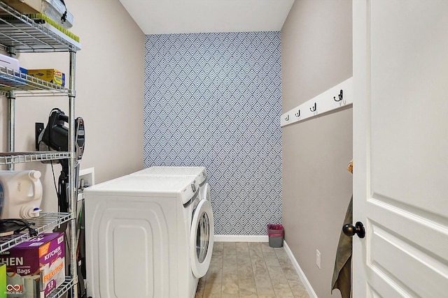 clothes washing area with laundry area, baseboards, and washer and clothes dryer