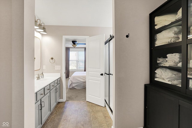 bathroom with a shower stall, connected bathroom, wood finished floors, vanity, and a ceiling fan