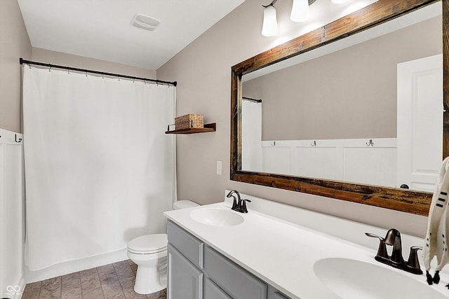 full bathroom featuring a sink, a shower with curtain, toilet, and double vanity