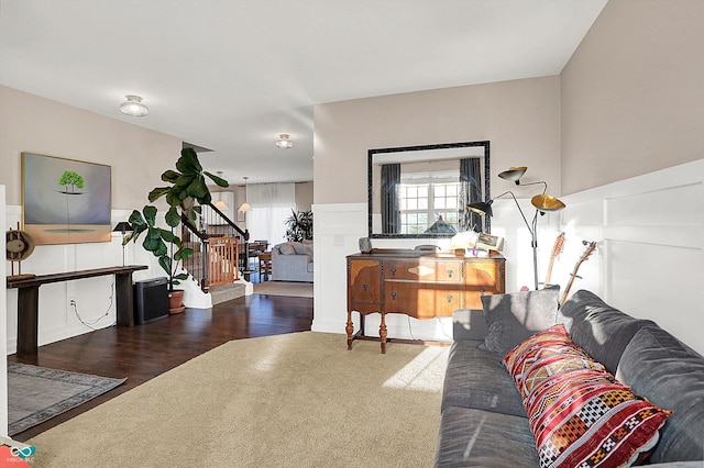 living room featuring stairway, carpet, wood finished floors, and wainscoting