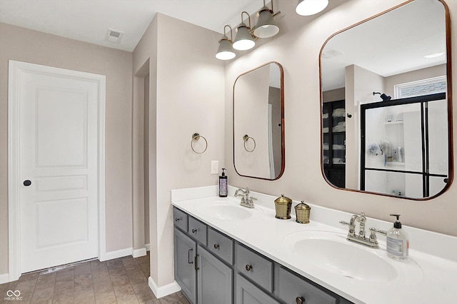 full bathroom with double vanity, baseboards, visible vents, and a sink