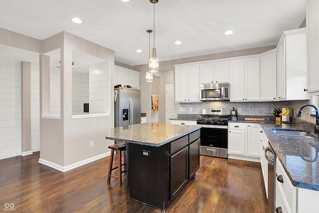 kitchen with dark wood finished floors, appliances with stainless steel finishes, a kitchen island, and a sink