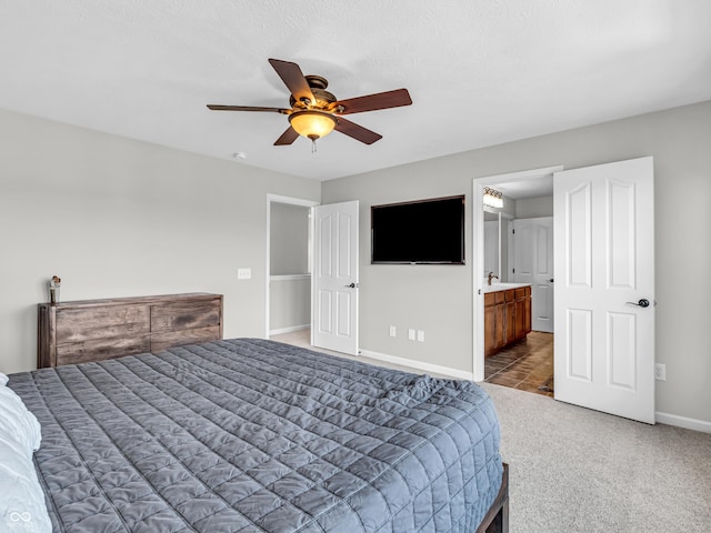 bedroom with ensuite bath, carpet flooring, a ceiling fan, and baseboards