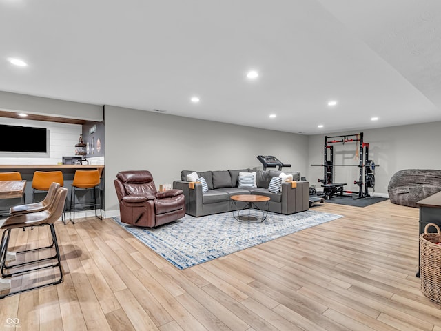 living room with recessed lighting, a dry bar, baseboards, and wood finished floors