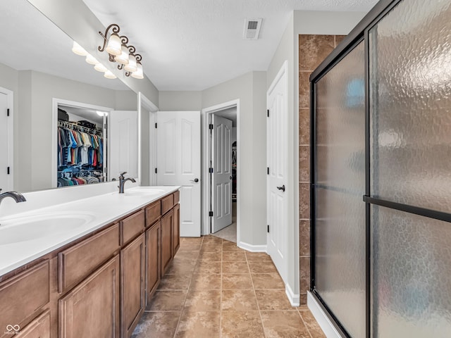 full bath featuring a spacious closet, visible vents, a shower stall, and a sink