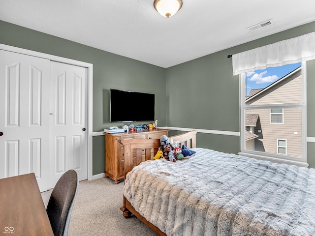 carpeted bedroom featuring baseboards, visible vents, and a closet