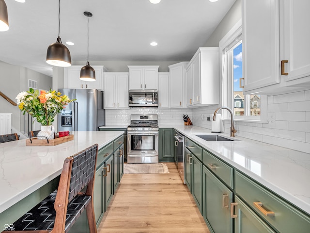 kitchen featuring green cabinets, light wood-type flooring, appliances with stainless steel finishes, white cabinetry, and a sink