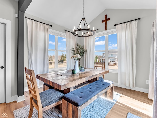 dining space featuring an inviting chandelier, vaulted ceiling, light wood-style flooring, and baseboards