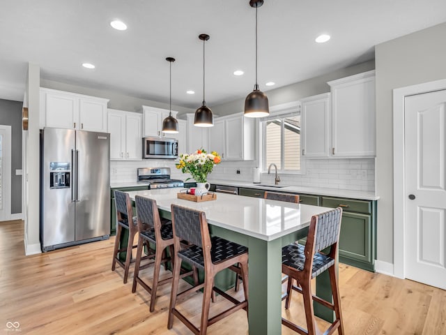 kitchen featuring a kitchen breakfast bar, appliances with stainless steel finishes, and white cabinetry