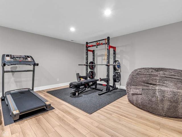 exercise area featuring recessed lighting, wood finished floors, and baseboards