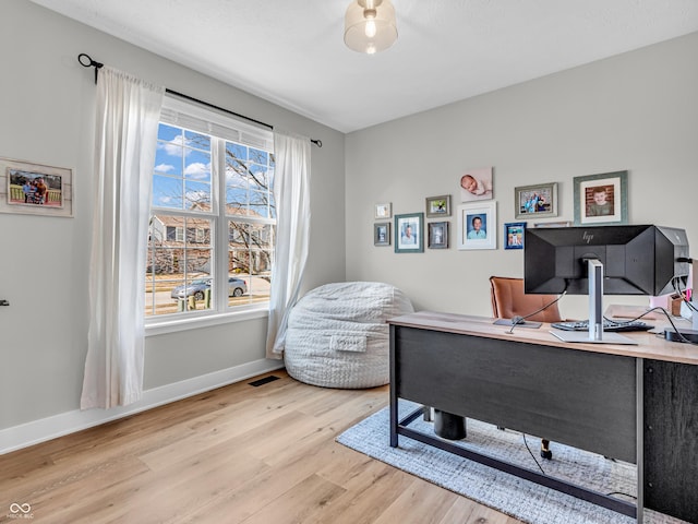 office space with light wood finished floors, visible vents, and baseboards