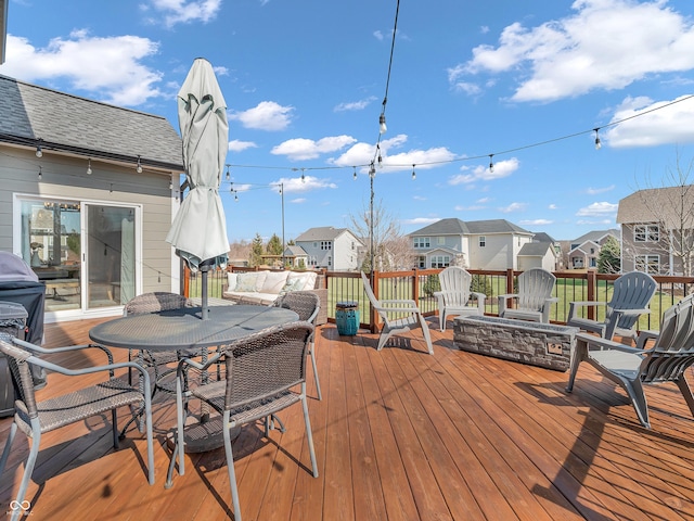 wooden deck with a residential view, outdoor dining space, and an outdoor fire pit