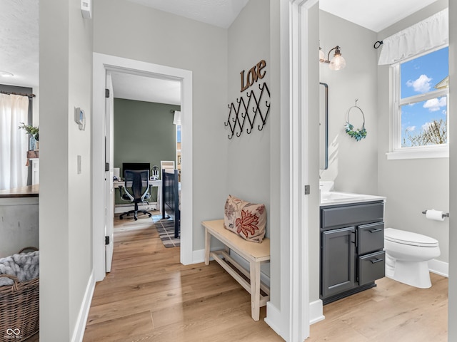 bathroom with vanity, toilet, wood finished floors, and baseboards