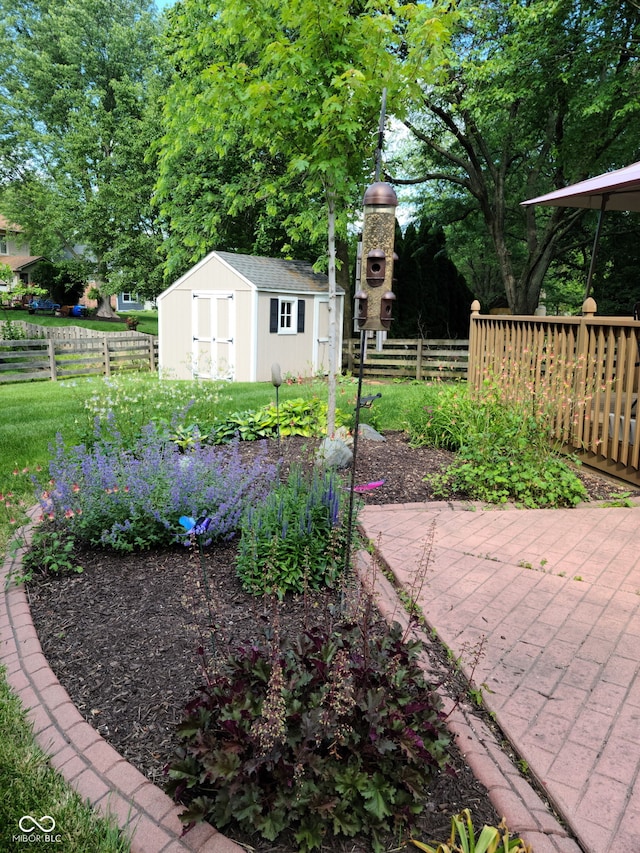 view of yard featuring an outbuilding, fence, a shed, and a patio area