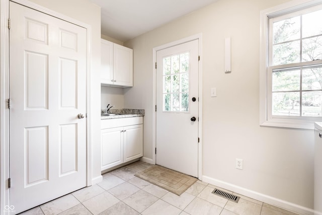 washroom with a sink, visible vents, baseboards, and light tile patterned flooring