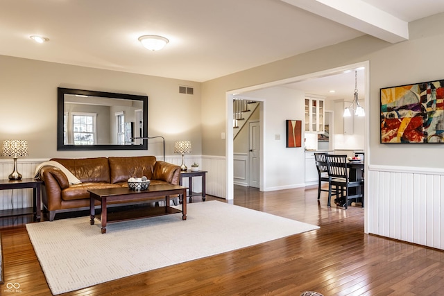 living area featuring beam ceiling, a wainscoted wall, visible vents, and dark wood-style flooring