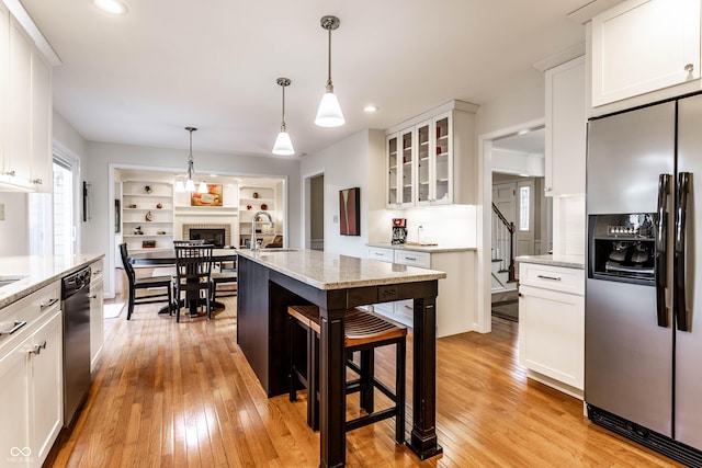 kitchen with a sink, stainless steel fridge with ice dispenser, light wood finished floors, glass insert cabinets, and dishwasher