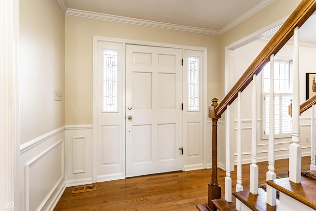 foyer with crown molding, stairway, wood finished floors, and visible vents