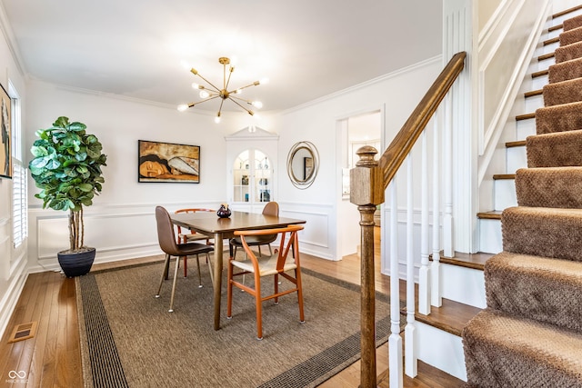 dining room featuring stairway, a decorative wall, visible vents, and ornamental molding