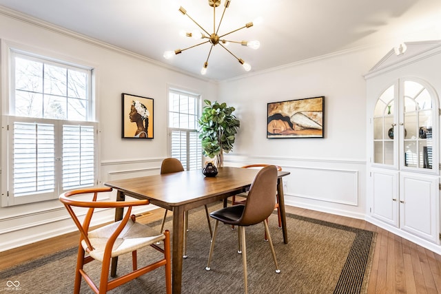 dining space featuring hardwood / wood-style floors, a notable chandelier, ornamental molding, and wainscoting