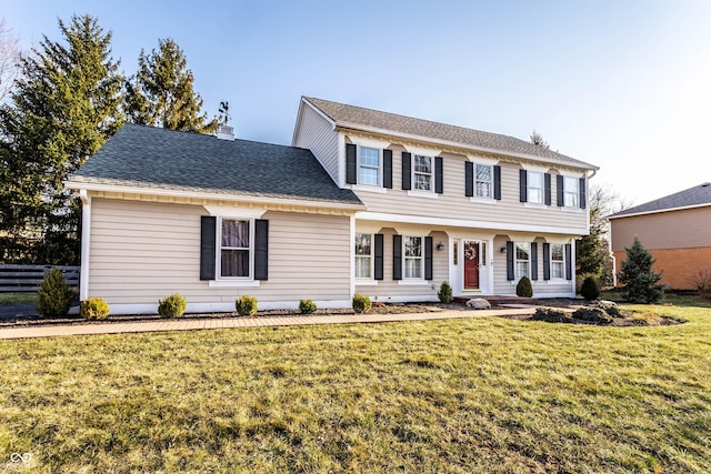 colonial home featuring roof with shingles, a chimney, and a front lawn