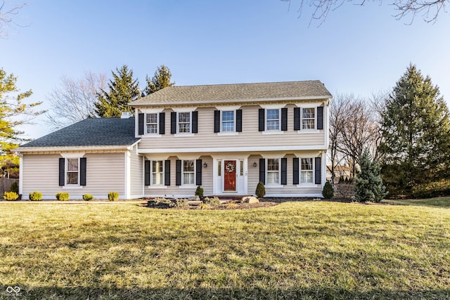 colonial-style house featuring a front lawn and roof with shingles