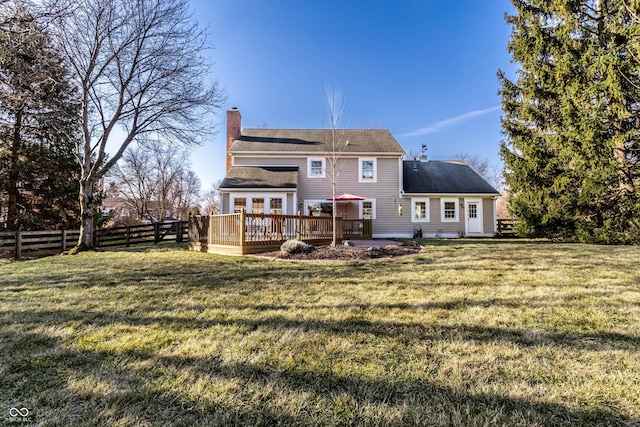 rear view of house with a shingled roof, fence, a chimney, a deck, and a yard